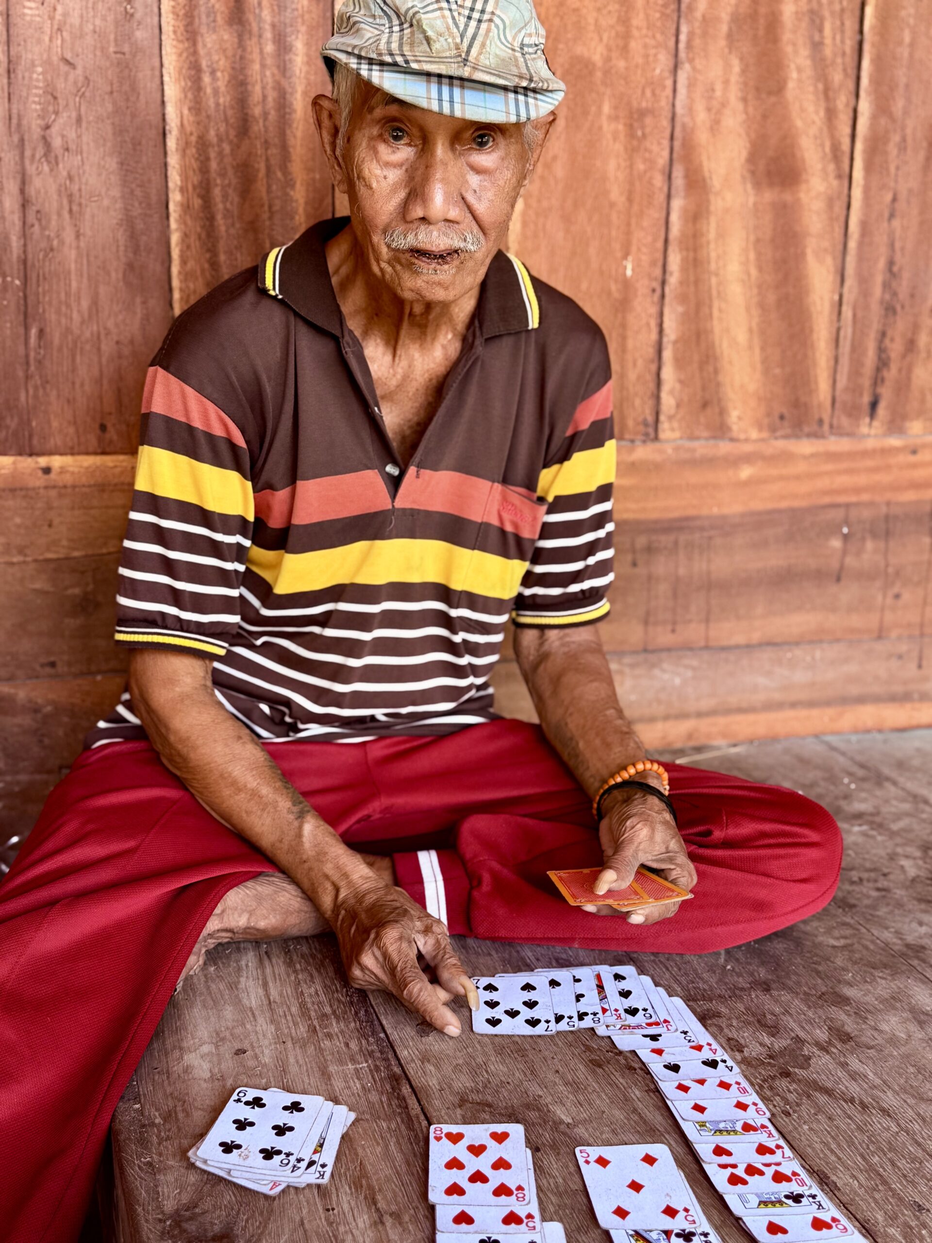 Un villageois de Sumba assis au sol, concentré sur une partie de cartes, dans une ambiance conviviale et authentique.