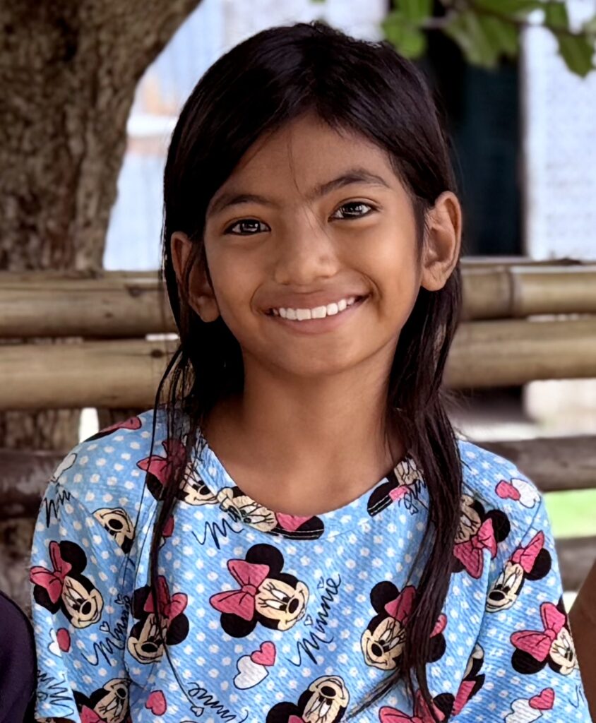 Portrait d'une jeune fille souriante ä Sumba, en t-shirt bleu Minnie Mouse.
