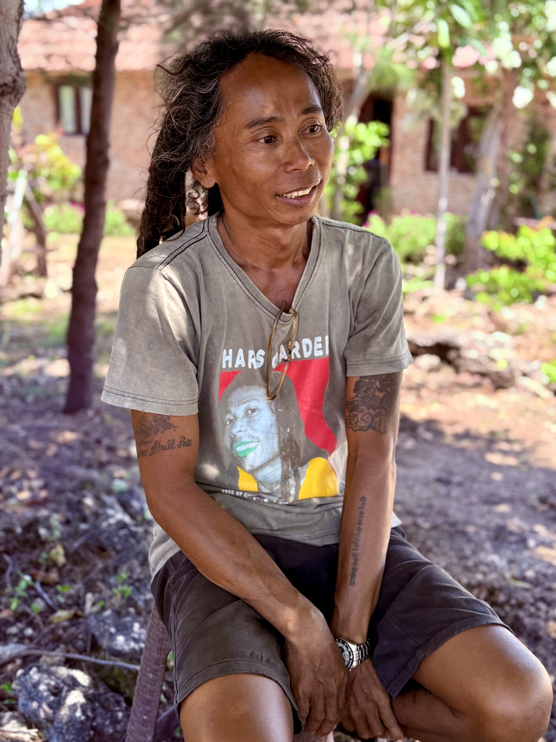 Portrait d'un habitant de Sumba assis dehors, sourire bienveillant.