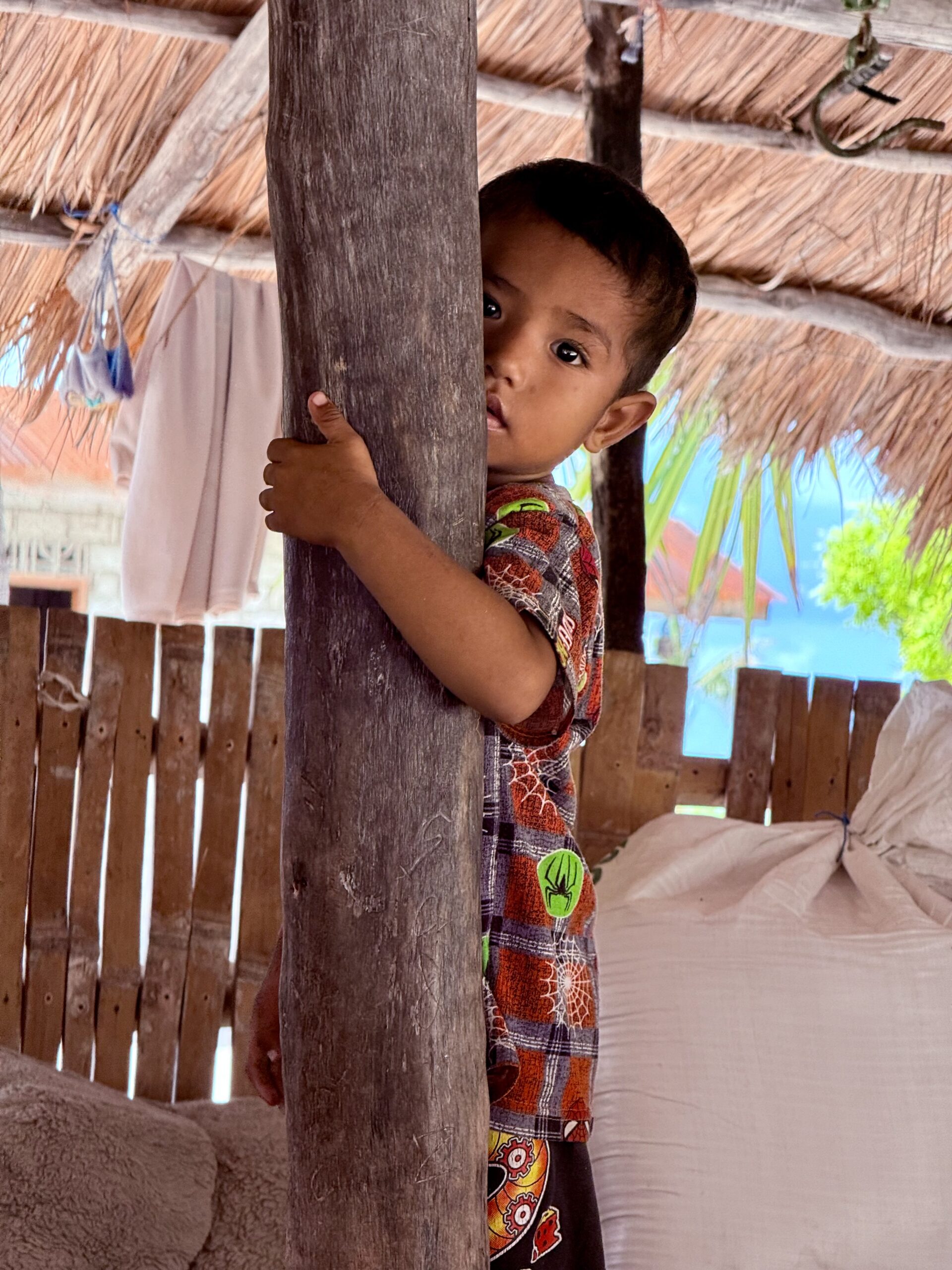 Jeune enfant de Sumba, observant timidement depuis une maison en bambou - immersion culturelle avec The World of Sumba