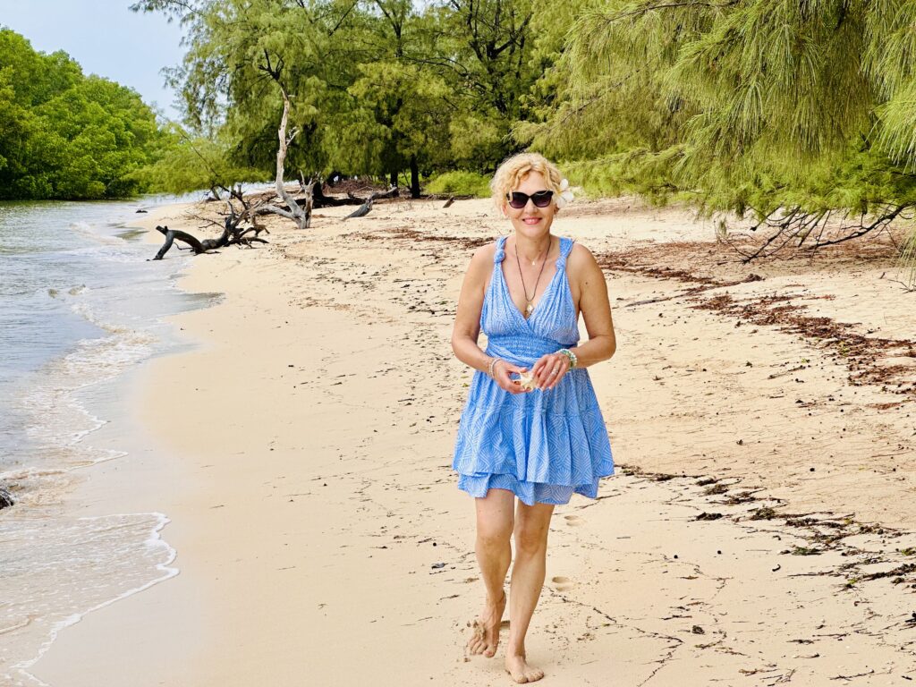 Cathy, fondatrice de The World of Sumba, marchant pieds nus sur une plage de Sumba.